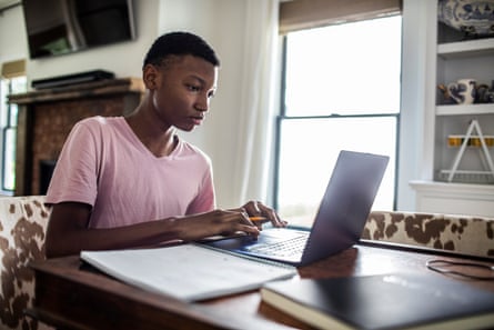 Teenage boy doing schoolwork at home using a laptop