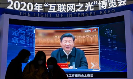 People stand in front of the screen playing Chinese President Xi Jinping message during an Internet Conference in China.