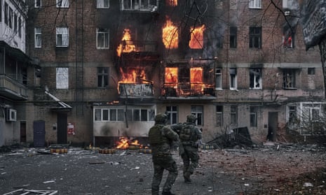 Ukrainian soldiers run to help people in an apartment house in fire after the Russian shelling in Bakhmut, Donetsk region.