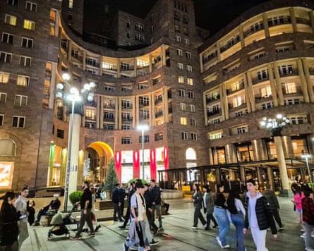 Passersby in front of a large building in Tashir Street at night