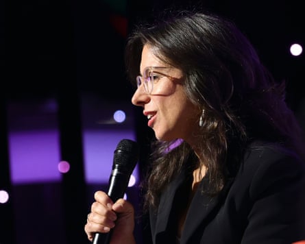 A woman talking into a microphone viewed from the side