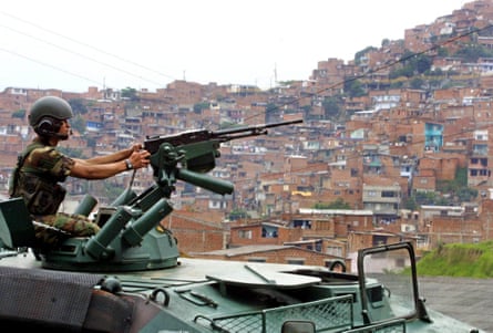 A mans the machine gun of a tank in a residential neighbourhood.