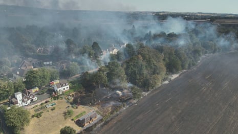 Smoke rises from trees and homes as firefighters tackle a blaze in the West Midlands.