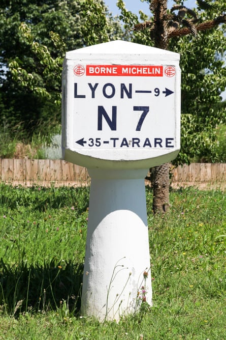 A white concrete roadside marker for the N7 saying distances to Lyon and Tarare.