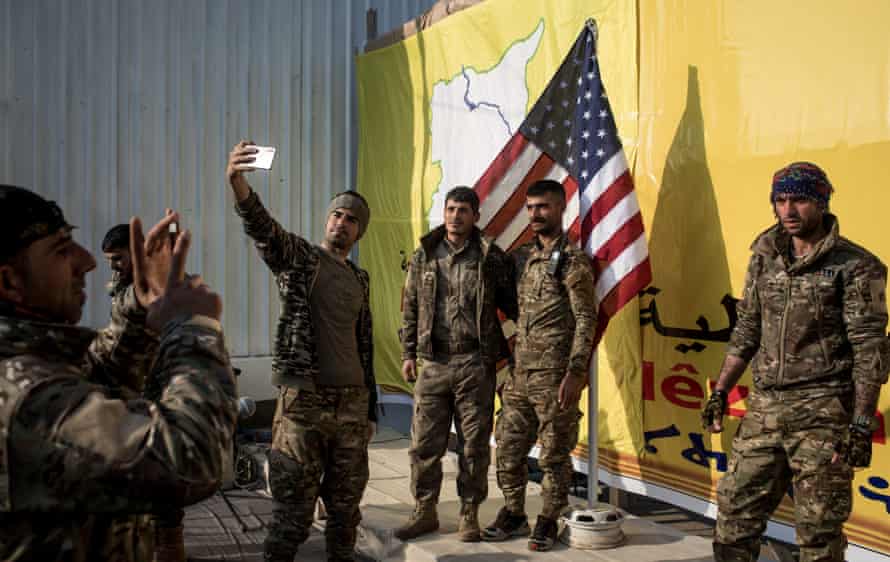 Fighters from the Kurdish-led Syrian Democratic Forces pose for a photo with the US flag after a ceremony announcing the defeat of Islamic State in Baghouz in March.