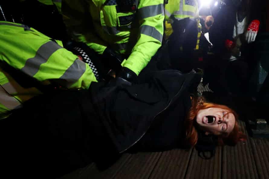Police detain a woman as people gather at a memorial site in Clapham Common Bandstand, following the kidnap and murder of Sarah Everard, in London, Britain March 13
