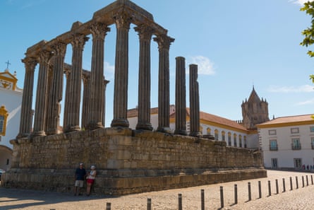 A couple leaning against the remains of a Roman temple with Corinthian columns
