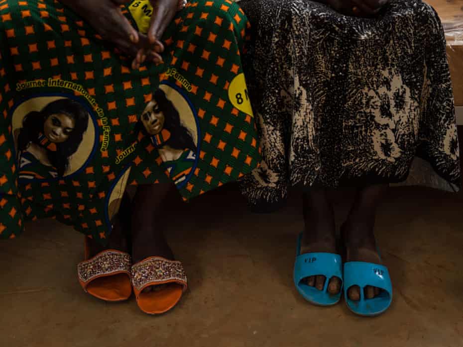 A picture of two women's feet in plastic sandals
