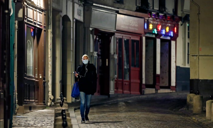 A woman walks on a deserted street in Montmartre before the 8pm curfew throughout Paris
