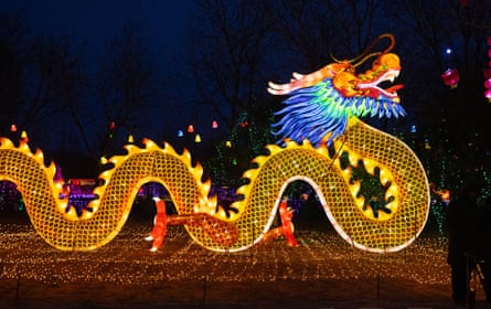 People stand by a dragon light installation in Beijing