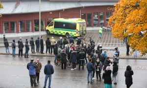 Θεατές στέκονται έξω μια αποκλεισμένη περιοχή μετά την επίθεση