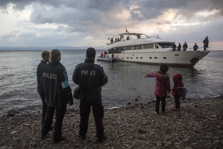 Frontex security personnel watch refugees and migrants disembarking from a yacht on Lesbos.