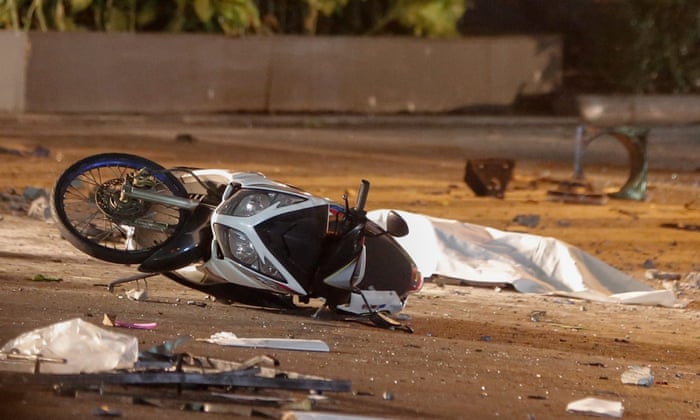 A body lies covered on the ground between damaged motorcycles at the scene of the explosion. Thais, Chinese and one Filipino are among the dead, officials have said