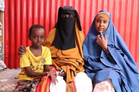 A woman in full veil sits between a young boy and a girl