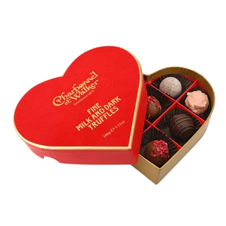 Charbonnel and Walker red velvet heart chocolate truffles box/ the box is open with the lid resting on the heart-shaped box where truffles are arranged in a grid.