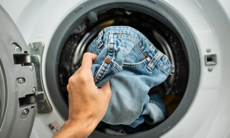 Jeans being loaded into a washing machine