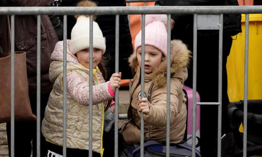 Two young girls look out from a barrier as they wait in a queue at the border crossing in Medyka, southeastern Poland, after fleeing Ukraine.