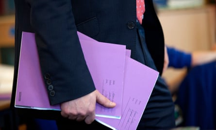 A teacher carrying school exercise books