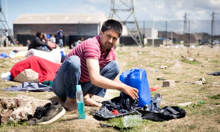 A refugee washing clothes on the ground at a Calais migrants’ camp, France, in August 2017.
