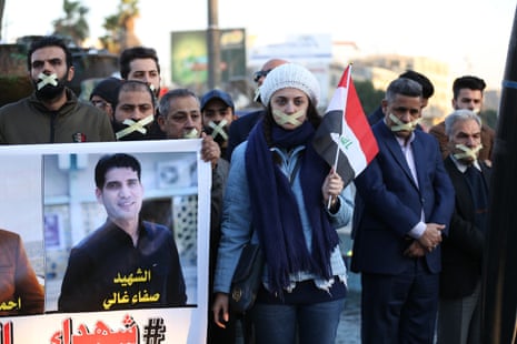 Protesters with tape over their mouths and Iraqi flags hold images of reporters killed in the city in the course of their work.