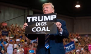 Donald Trump holds up a “Trump Digs Coal” sign as he arrives to speak during a Make America Great Again Rally at Big Sandy Superstore Arena in Huntington, West Virginia, August 3, 2017.