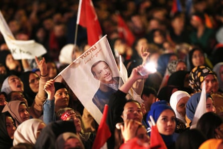 Supporters wave flags and banners as the Turkish president, Recep Tayyip Erdoğan, gives a speech.