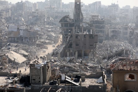 Aerial view of people walking along a path cleared through the rubble