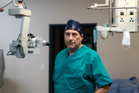A man in green surgical scrubs stands in an operating theatre