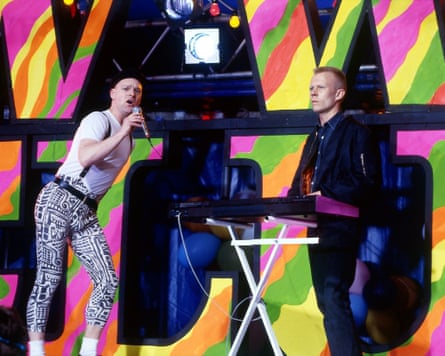 Bell and Clarke on stage performing, in front of bold-coloured large letters