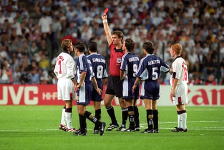 Referee Kim Milton Nielsen shows the red card to David Beckham while being surrounded by players