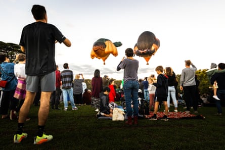 Members of the crowd are seen observing and taking photos of Skywhale and Skywhalepapa, over Melbourne on March 19, 2022