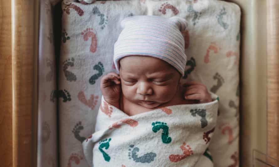Overhead view of newborn boy with hat in hospital bassinet