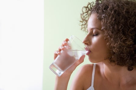 A woman drinking a glass of water.