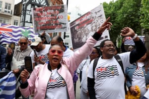 Members of the British Chagossian community demonstrate, holding signs and flags