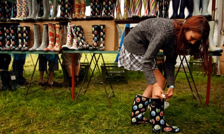 A festival-goer tries on wellington boots at the Glastonbury Festival, UK.
