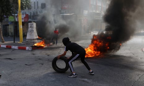 A protester rolls a tire during clashes with Israelis in the West Bank city of Hebron on Friday