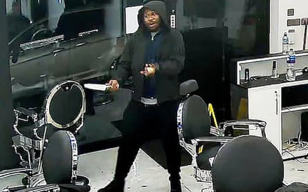 A man in a black hoodie holding a large knife inside the barber’s