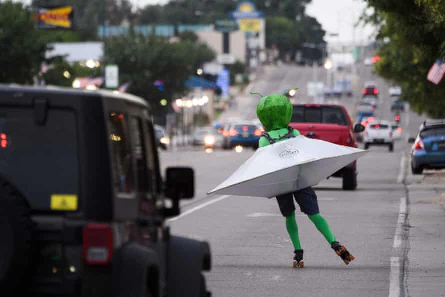 Une personne portant un costume extraterrestre dans une soucoupe volante patins à roulettes à travers la circulation dans la rue Main pendant le Festival UFO à Roswell, Nouveau Mexique