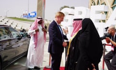 Oliver Dowden shakes hands with Saudi officials outside a building where a large freestanding lettering saying Great Futures can be seen