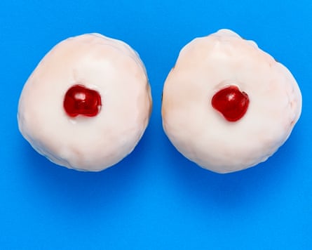 Two white cakes with glace cherries in their centre, against blue background