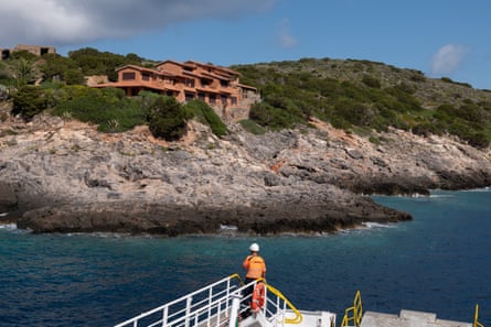 A small collection of dwellings on a rocky outcrop can be seen from a boat