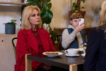 Joanna Lumley sits at a table in the comedy Amandaland.