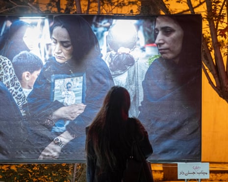An Iranian woman stands in front of a banner in Tehran depicting portraits of the mothers of schoolgirls killed in a 28 February strike on Shajareh Tayyebeh school in Minab, which killed up to 168 people