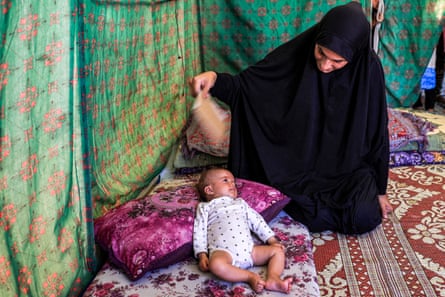 a woman fans a baby as the baby lays on a pillow