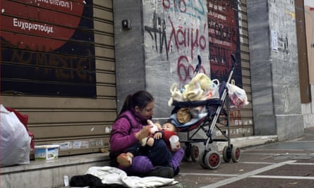 A woman with a child begs on an Athens street.