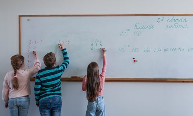 यूक्रेनी स्कूली बच्चे बर्लिक में कक्षा में एक व्हाइटबोर्ड पर लिखते हैं