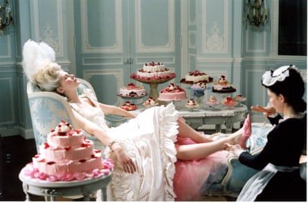 Kirsten Dunst as Marie Antoinette next to a maid and surrounded by cakes.
