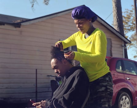 Precious Campbell, 33, braids 17-year-old Paul Kimble’s hair in front of her family’s property in Mossville.