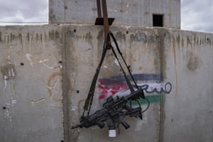 Two M-16 rifles hang on a wall with a graffiti featuring the Palestinian flag