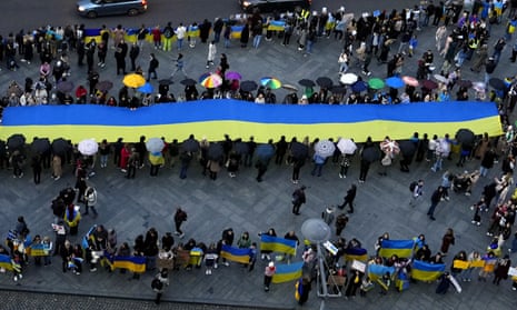 People hold up a large Ukrainian flag as they gather for a protest in Prague on Tuesday